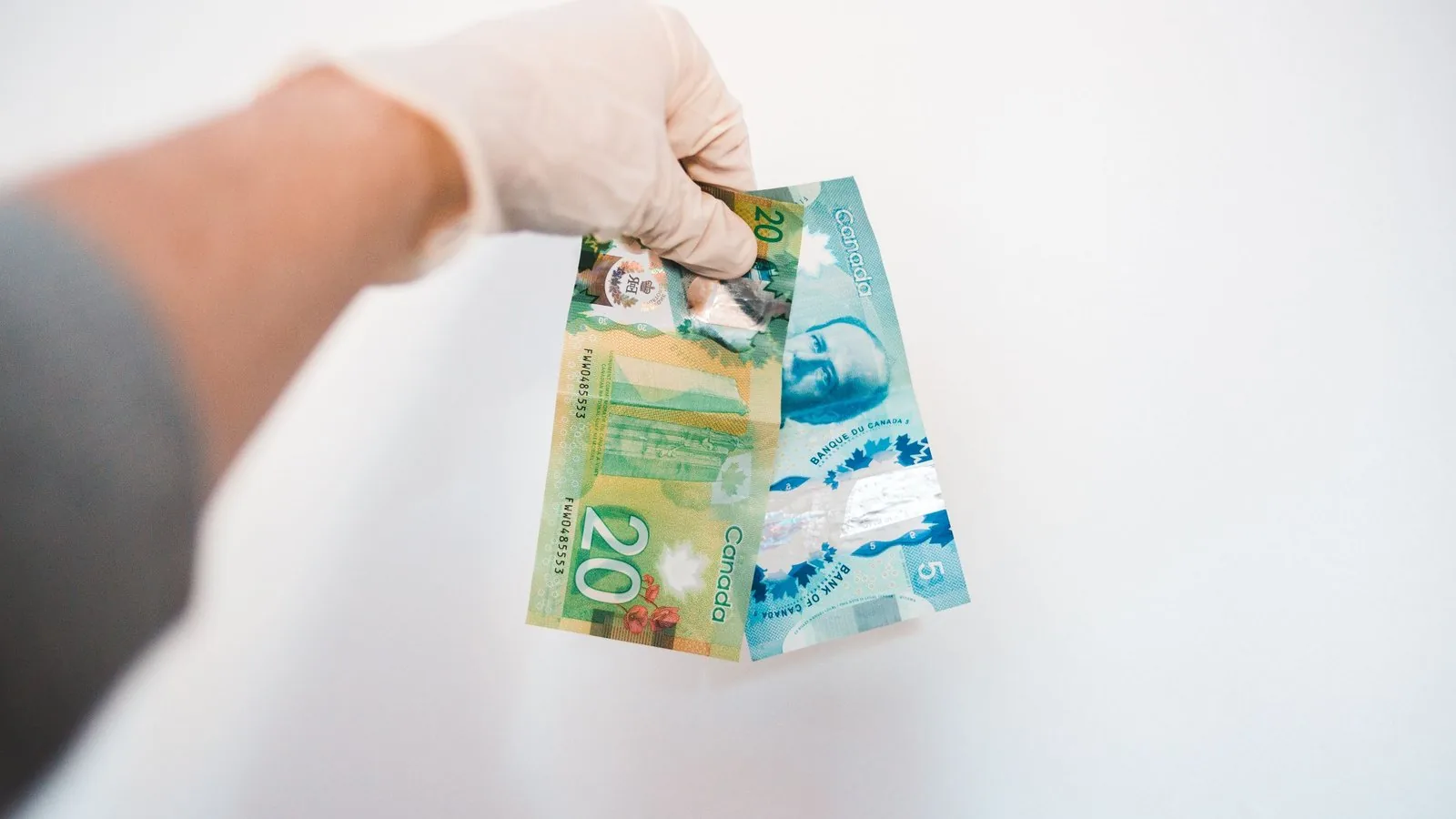 Dłoń trzymająca polskie banknoty na jasnym tle