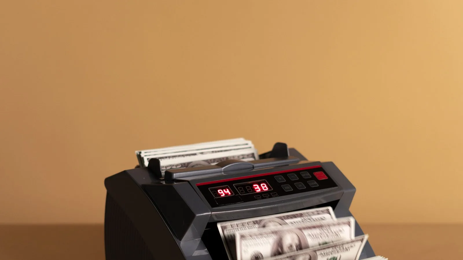 Maszyna licząca banknoty na brązowym tle